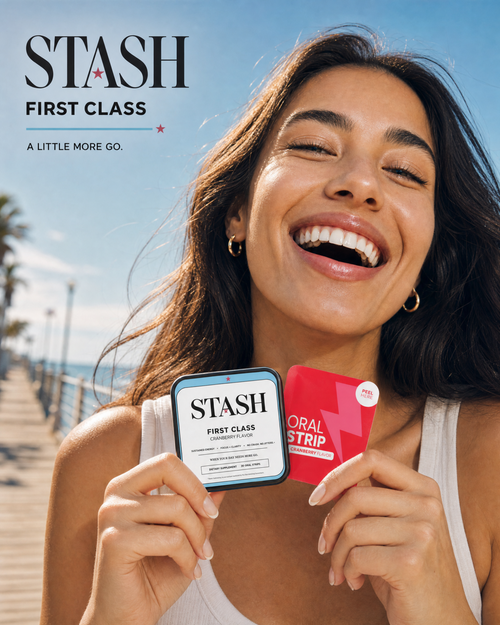 Smiling woman holding STASH FIRST CLASS cranberry energy strips by the coast